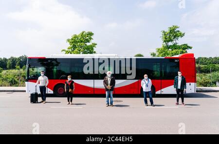 Cinq passagers portant des masques de protection debout dans une rangée devant l'autobus public, Espagne Banque D'Images