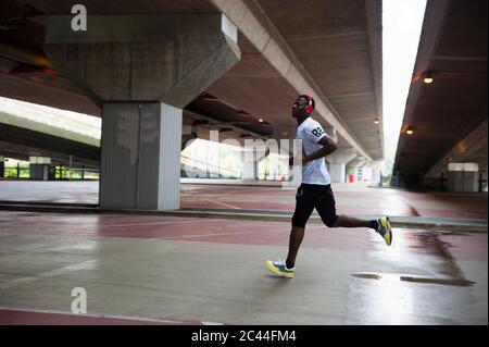 Jeune homme avec casque de jogging dans la ville Banque D'Images