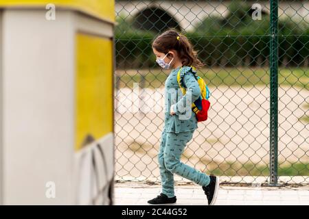 Fille portant un masque et marchant avec sac à dos à l'extérieur Banque D'Images