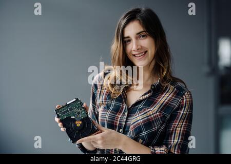 Portrait d'une jeune femme souriante montrant le disque dur Banque D'Images