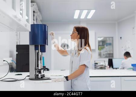 Scientifique féminin utilisant l'équipement pendant son travail en laboratoire Banque D'Images