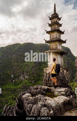 Vietnam, province de Ninh Binh, Ninh Binh, randonneur mâle se tenant à côté de la tour des grottes de Mua Banque D'Images