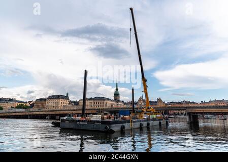 Stockholm, Suède - 8 août 2019 : barge de construction flottante avec une grue sur le port contre le paysage urbain de Gamla Stan à Stockholm Banque D'Images