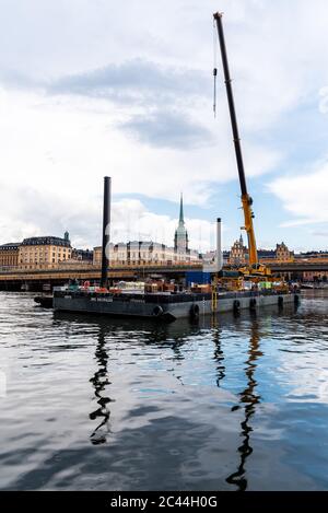 Stockholm, Suède - 8 août 2019 : barge de construction flottante avec une grue sur le port contre le paysage urbain de Gamla Stan à Stockholm Banque D'Images