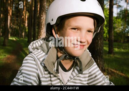 Joyeux garçon portant un casque de cyclisme en forêt Banque D'Images