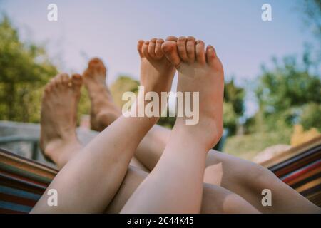 Pieds de garçon se détendant avec la mère sur le hamac dans le jardin Banque D'Images