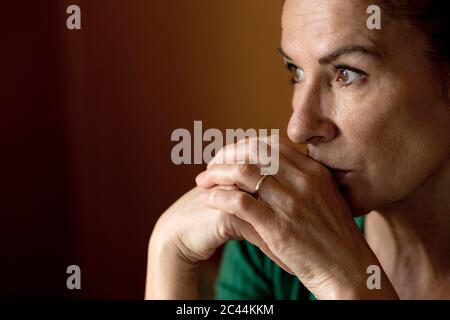 Femme mûre et attentionnés qui regarde loin de chez elle pendant le couvre-feu Banque D'Images