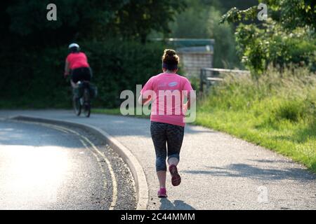 Une coureuse et cycliste tôt le matin pendant le confinement de Covid-19, Warwickshire, Royaume-Uni Banque D'Images