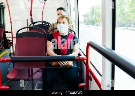 Portrait de la femme adulte portant un masque de protection dans un bus public, Espagne Banque D'Images