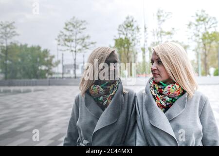 Portrait de femme blonde penchée contre le devant du verre regardant son image miroir Banque D'Images