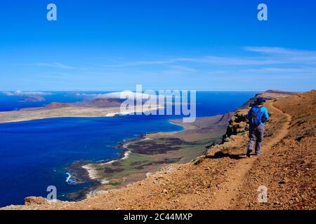 Espagne, Canaries, femme backpacker randonnées le long du bord de la falaise côtière de l'île de La Graciosa Banque D'Images