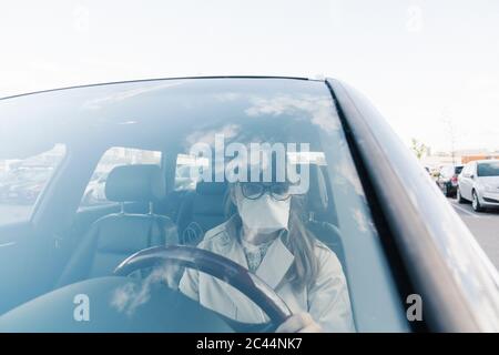 Femme portant un masque dans une voiture Banque D'Images