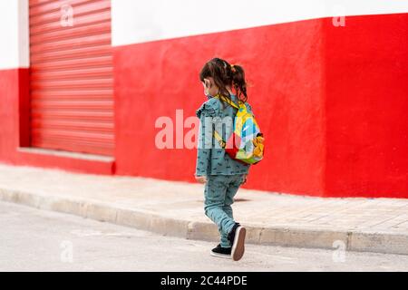 Fille marchant avec sac à dos et masque dans la rue Banque D'Images