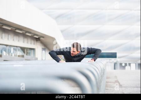 Jeune homme qui fait des push-up sur des barres métalliques Banque D'Images