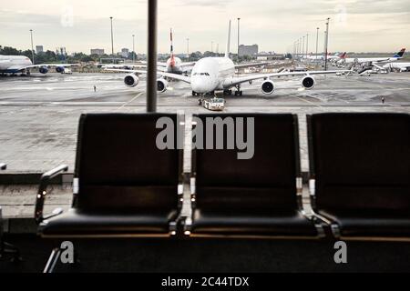 Afrique du Sud, Johannesburg, avion sur tarmac vu depuis le terminal de l'aéroport avec des chaises vides en premier plan Banque D'Images