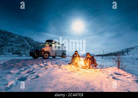 Campeurs au feu de camp en hiver paysage dans la nuit polaire, Kilpisjaervi, Enontekioe, Finlande Banque D'Images