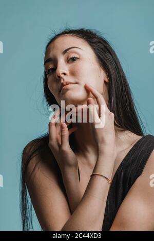 Belle femme touchant son visage devant un fond vert Banque D'Images