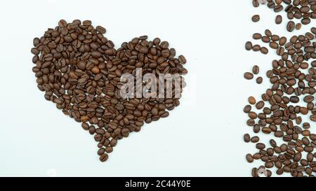 Beaucoup de grains de café sur le dorregrnd blanc. Cœur de grains de café. Grains de café dans la tasse. Photo de haute qualité Banque D'Images