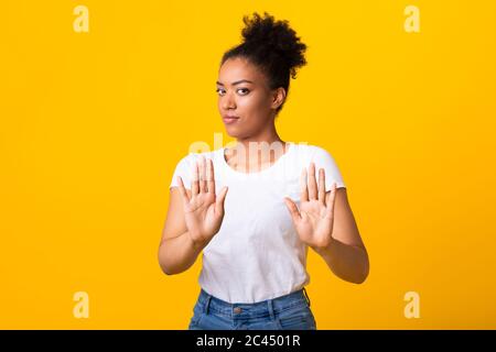 Fille noire sérieuse montrant un panneau d'arrêt avec deux mains Banque D'Images