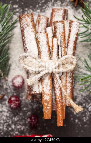 Des bâtons de cannelle sont mis en gros sur une table de cuisine du nouvel an. Noël, branches de sapin, gros plan Banque D'Images