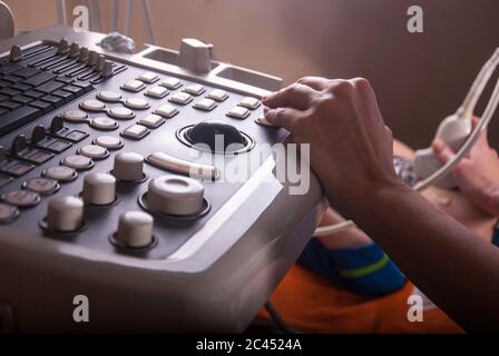 Un médecin échographin examine le cou et l'abdomen d'un enfant à l'aide d'une électrode à ultrasons Banque D'Images