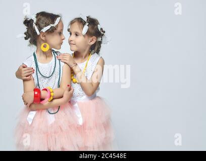 Deux petites filles jouent avec le maquillage de leur mère. Elles posent et essayent d'être des adultes.Studio, dos blanc Banque D'Images