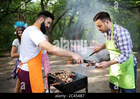 Les amis s'amusant dans la nature faire un barbecue Banque D'Images