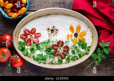 Pâte maison pour une délicieuse focaccia italienne. La décoration est faite de tomates cerises, d'olives et d'herbes fraîches. Banque D'Images