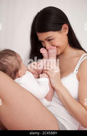 Mère joue avec bébé au lit Banque D'Images