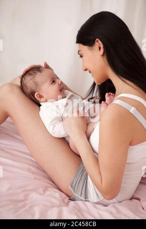 Mère joue avec bébé au lit Banque D'Images