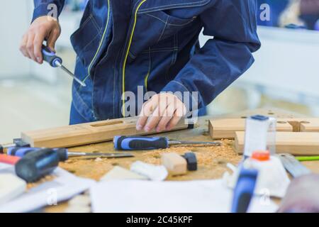 Menuisier professionnel utilisant le burin pour sculpter le bois sur établi rugueux à l'atelier. Design, menuiserie, savoir-faire et travail à la main Banque D'Images