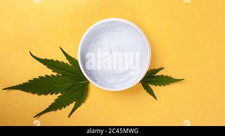 cosmétiques de soins de la peau avec extrait de marijuana, beauté, gommage corporel avec feuille de cannabis sur fond jaune vue du dessus. Banque D'Images
