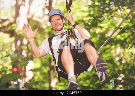 Homme d'âge moyen qui se renard volant dans un parc forestier à cordes Banque D'Images