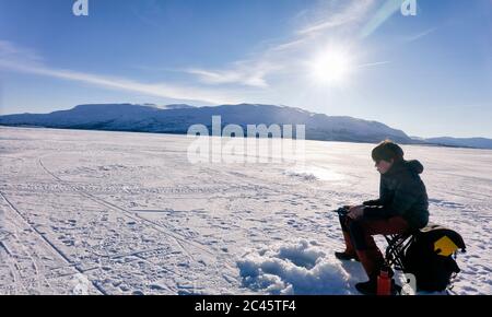 Garçon pêche sur glace sur un lac gelé à Vasterbotten LAN, Suède. Banque D'Images