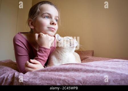 Portrait de fille et chat blanc et gingembre couché sur le lit. Banque D'Images