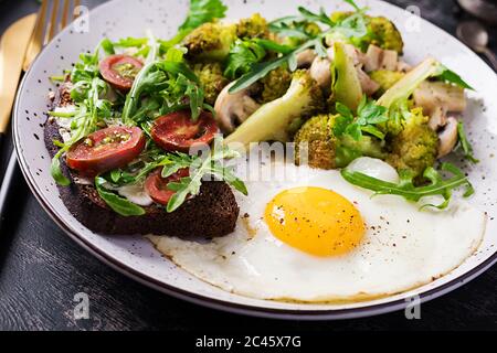 Petit déjeuner avec œuf frit, brocoli, champignons et sandwich aux tomates. Alimentation saine et équilibrée. Banque D'Images