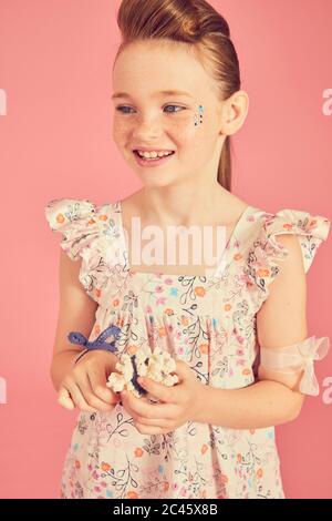 Portrait de fille de brunette souriante portant une robe à volants avec motif floral sur fond rose. Banque D'Images