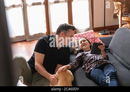 Père et fille sur le canapé du salon pendant le confinement du coronavirus. Banque D'Images