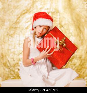 Jeune fille, âge scolaire, tenant un cadeau de Noël, portant un chapeau de Noël devant le canal festif Banque D'Images