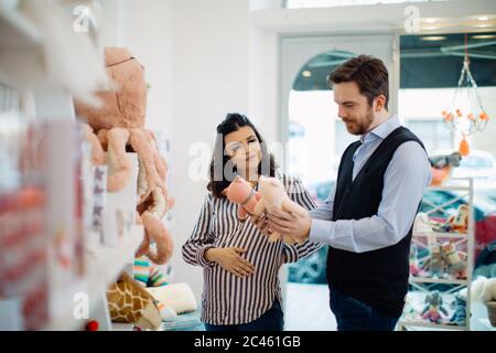 Mari et femme enceinte shopping pour les jouets mous Banque D'Images