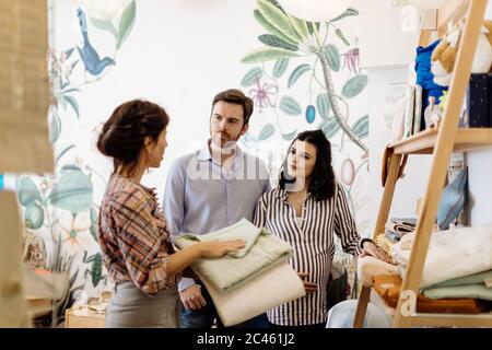 Shop keeper affiche les items à pregnant couple Banque D'Images