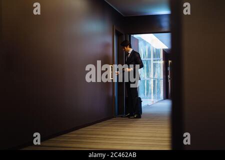 Avec l'homme d'entrer dans une valise à roulettes chambre hôtel Banque D'Images