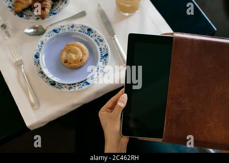 La main de femme dépose digital tablet à partir de cas, tandis que le petit-déjeuner à boutique hotel en italie Banque D'Images