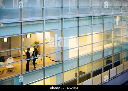 Businessman and businesswoman having discussion par fenêtre Banque D'Images