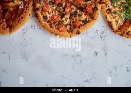 3 différents types de pizzas placés dans une ligne blanche sur table rouillée Banque D'Images