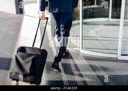 Avec l'homme d'entrer dans une valise à roulettes portes tournantes de la construction Banque D'Images