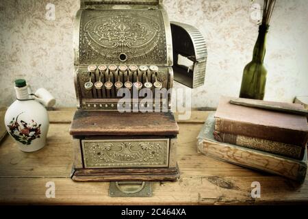 KOLMANSKOP,NAMIBIE -27 JANV. 2016: Caisse d'époque sur table en bois dans un bureau d'affaires de style rétro. Pot et tasse en argile, livres et verre non imprimés Banque D'Images