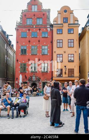 Stortorget Squartow dans la vieille ville Gamla Stan. Un homme vêtu des vêtements d'un moine médiéval raconte des histoires intéressantes du passé à un groupe de touris Banque D'Images