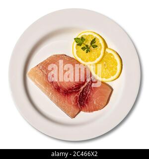 Macro gros plan d'une assiette avec une tranche d'espadon frais et cru. Plat garni de deux tranches rondes de citron et de feuilles de persil. Isolé sur fond blanc Banque D'Images