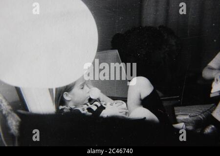 Belle photographie en noir et blanc des années 1970 de deux filles qui traînaient à la maison tout en regardant la télévision. Banque D'Images